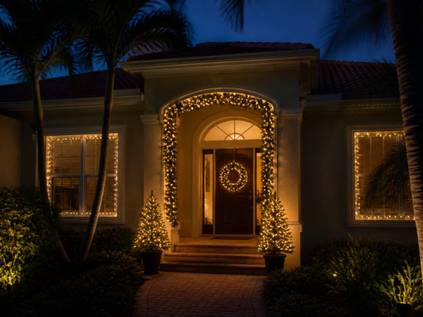 Concept: a front entry with lit garland arch, wreath and outlined windows